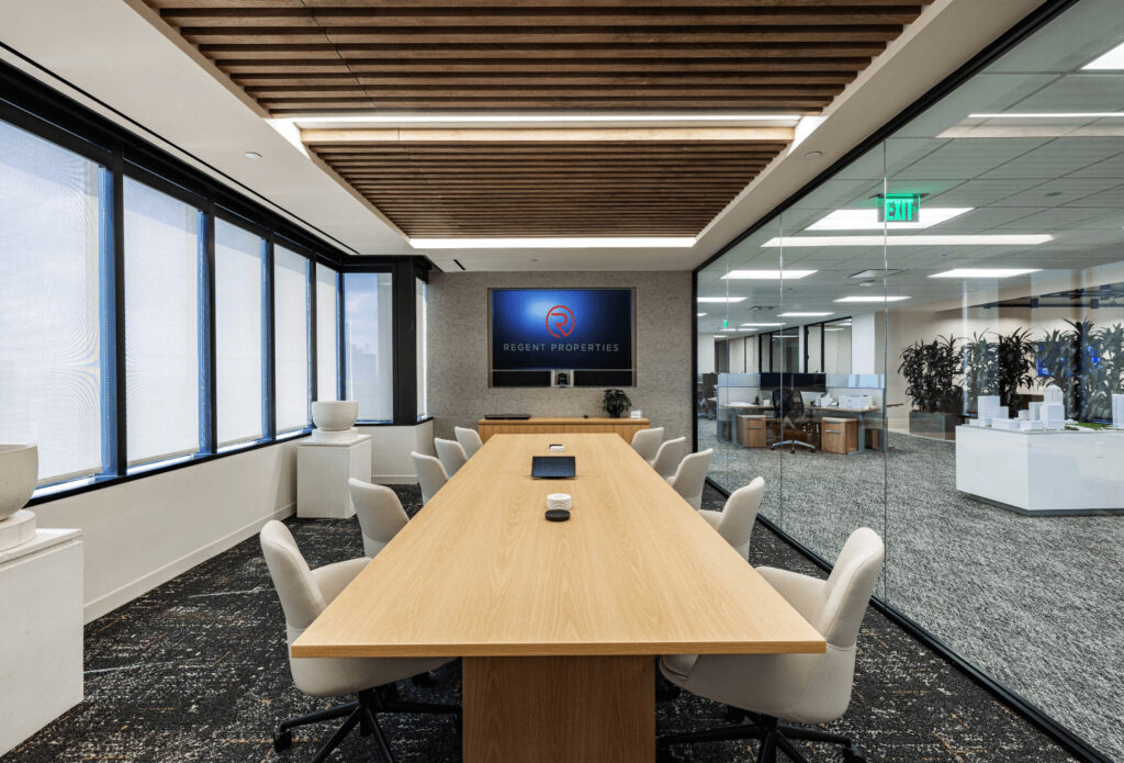Regent Offices modern conference room with a long wooden table, chairs, large windows, and a logo on the wall.