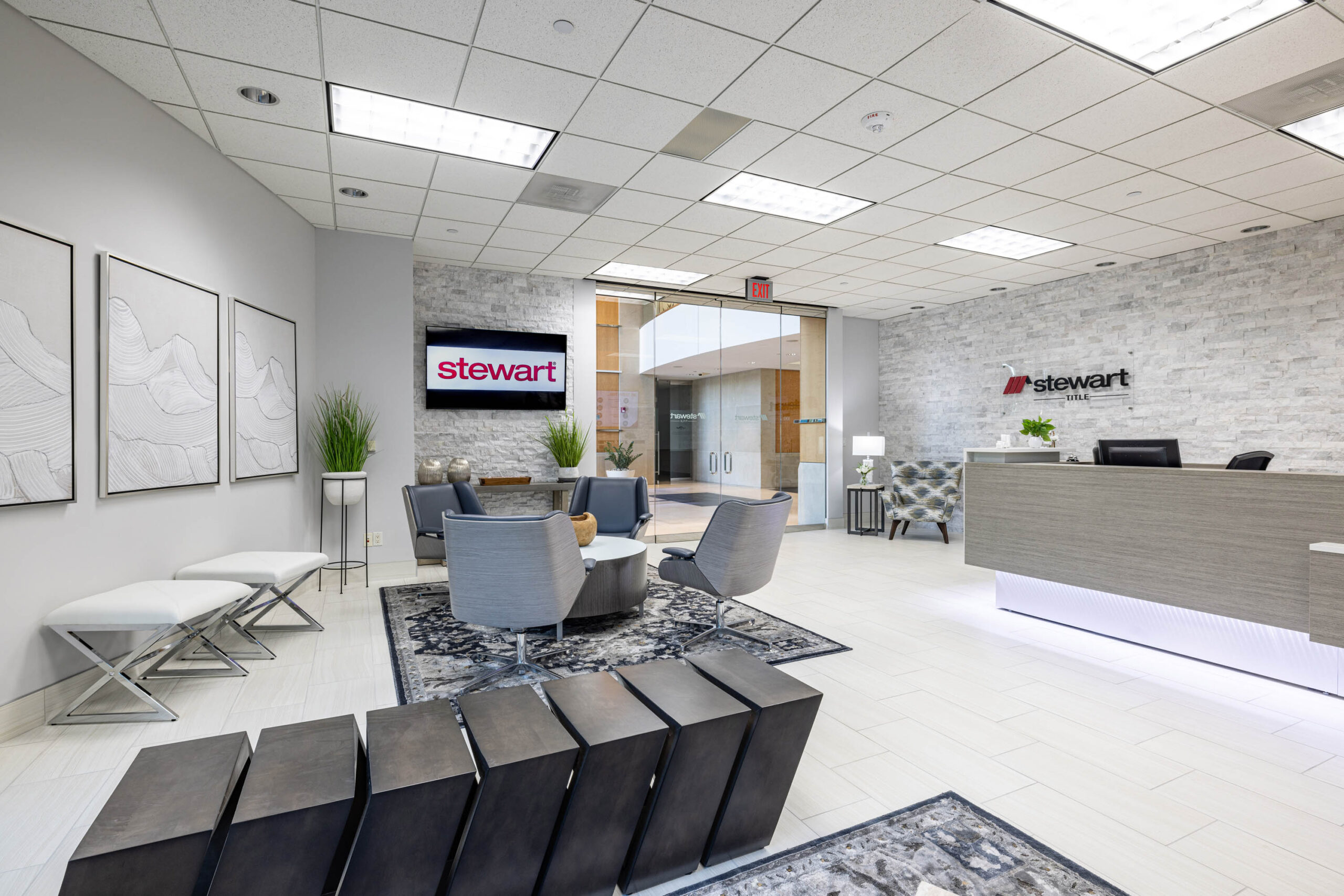 Modern office lobby with gray seating, decorative wall art, and a Stewart Title reception desk along the Tollway.