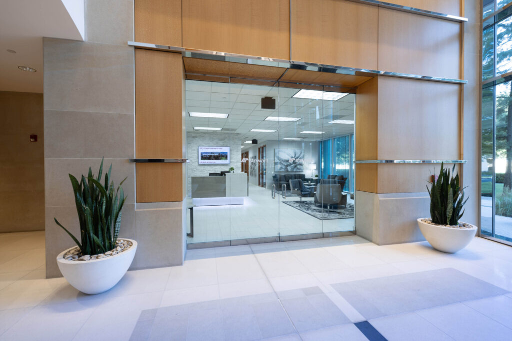 Modern office entrance with glass doors, potted plants, and a Stewart Title reception area beyond.